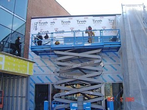 person on a lift installing metal wall panels